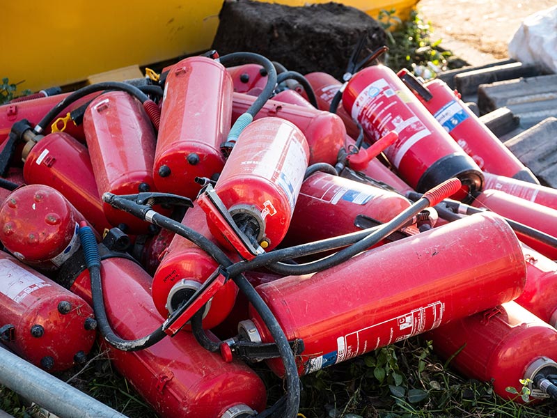 Mehrere alte Feuerlöscher liegen zur Entsorgung auf einem Haufen.