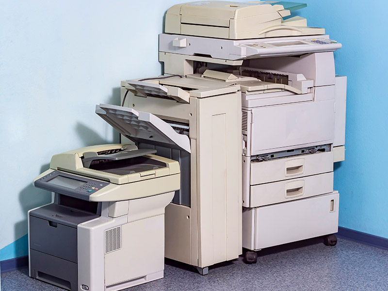 Alter Drucker steht in einer Ecke in einem Büro.