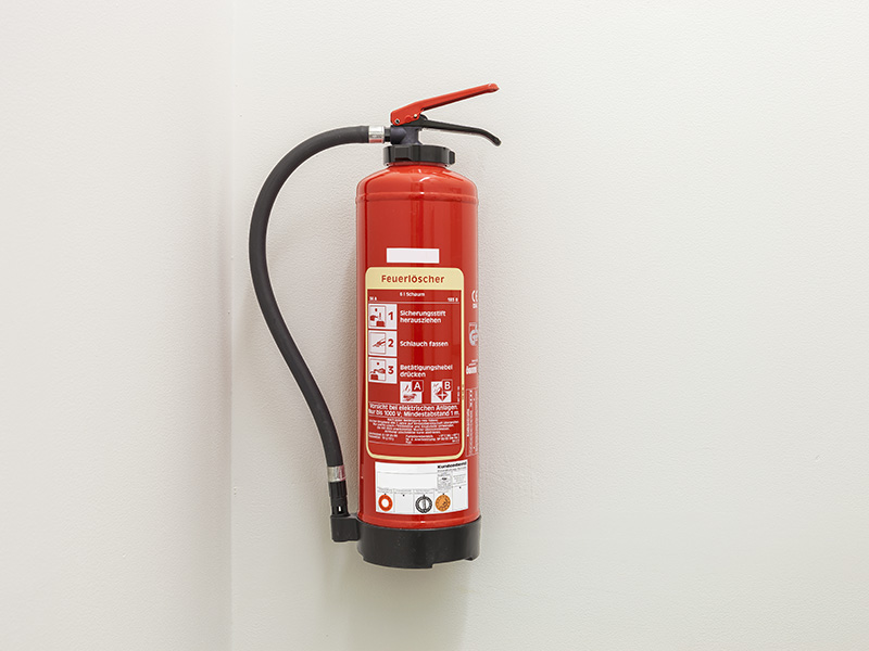 Feuerlöscher hängt an einer Wand in einem Gebäude.