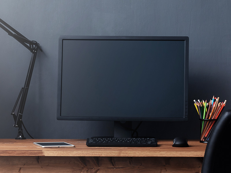 Ein Monitor mit schwarzem Bildschirm steht auf einem Schreibtisch.