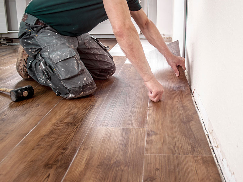 Person renoviert ein Zimmer und hat einen Vinylboden in der Hand.